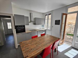 a kitchen with a wooden table and red chairs at Maison Val de Cher in Noyers-sur-Cher