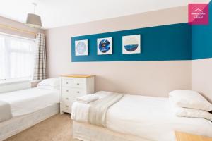 2 łóżka w sypialni z niebiesko-białymi ścianami w obiekcie Long Stays by NEC, HS2 and JLR - Driveway and Garden w mieście Solihull
