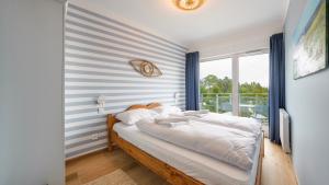 a bedroom with a bed with a striped wall at Apartamenty Sun & Snow Let's Sea Baltic Park in Gąski