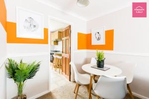 jadalnia z pomarańczowymi i białymi ścianami oraz stołem i krzesłami w obiekcie Long Stays by NEC, HS2 and JLR - Driveway and Garden w mieście Solihull