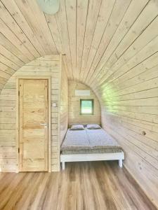 una piccola camera da letto con un letto in una camera in legno di Palūšės Kempingas (nameliai) a Palūšė