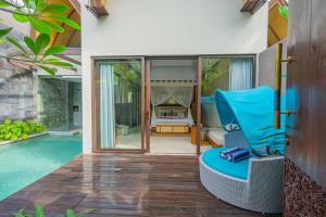 a villa with a swimming pool and a blue chair at Lalasa Villas Canggu in Canggu