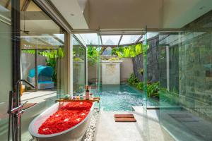 a bathroom with a tub and a swimming pool at Lalasa Villas Canggu in Canggu