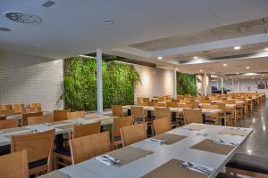 uma sala de jantar com mesas, cadeiras e plantas em Don Juan Resort Affiliated by FERGUS em Lloret de Mar