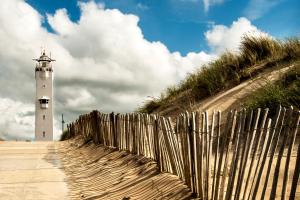 einen Zaun neben einem Leuchtturm am Strand in der Unterkunft Hotel Astoria in Noordwijk aan Zee