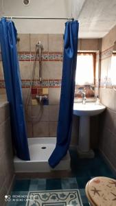 La salle de bains est pourvue d'un rideau de douche bleu à côté d'un lavabo. dans l'établissement Charmante petite maison de pêcheur - Proche Ile de Bréhat et GR34, à Lézardrieux