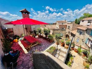 un patio al aire libre con una sombrilla roja y una mesa en La Chambre Spa la maison Searle à Tourtour, en Tourtour