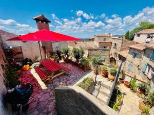 an outdoor patio with a red umbrella and a table at La Chambre Spa la maison Searle à Tourtour in Tourtour