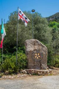 dos banderas y un monumento de piedra con bandera en Hotel Oleandro en Villasimius