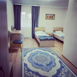 a room with two beds and a rug at Hotel Дар-Ай in Kostanay