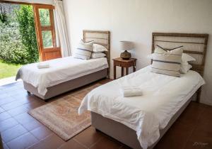 two beds sitting in a room with a window at Karoo House Collection - Riverdene Lodge in Nieu-Bethesda