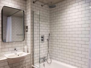 a bathroom with a sink and a tub and a mirror at Dukes Head Hotel in Croydon