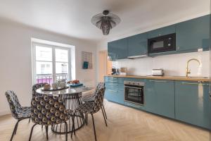 a kitchen with blue cabinets and a table and chairs at Sweet Inn - Lescot II in Paris