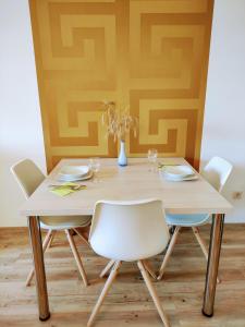 a dining room table with white chairs and a yellow wall at Apartma MAX in Moravske-Toplice