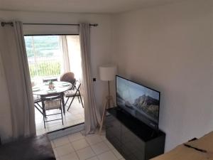 ein Wohnzimmer mit einem Flachbild-TV und einem Tisch in der Unterkunft Le '47' Village de Campagne, 83310 Cogolin in Cogolin