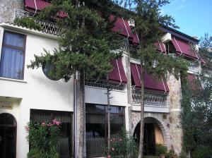 a white building with a tree in front of it at Hotel Baron in Tirana