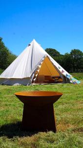 a tent in a field with a table in the grass at Dorset Glamping Fields in Corfe Mullen