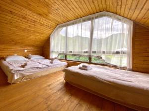 two beds in a room with a large window at Villa Achkhoti (Kazbegi) in Kazbegi