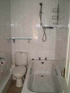 a white bathroom with a toilet and a bath tub at The Calf Suite in Aberystwyth
