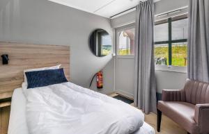 a bedroom with a bed and a chair and windows at Frich's Rudshøgda in Ringsaker +10 photos