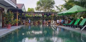 a pool of water with people sitting around tables and chairs at Hoi an Osaka Riverside Villa & Spa in Hoi An