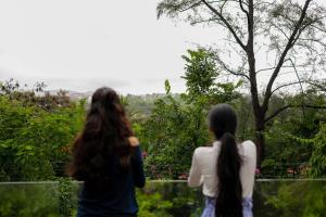 two girls are looking out at a garden at StayVista's Valencia Villa with Gazebo and Indoor Games in Lonavala