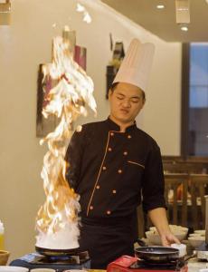 a man in a chefs hat standing in front of a cake at Merry Land Hotel Da Nang in Danang