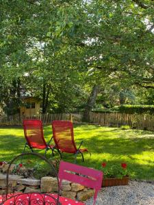 two red chairs sitting in a yard next to a garden at Gites Graines du Jura in Chille