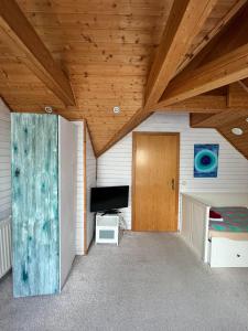 Habitación con techo de madera, puerta y TV. en B&B Chardas, en Bük