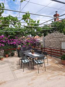 een tafel en stoelen op een patio met bloemen bij Old town rooms in Rab