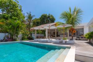 卡朗阿森Villa Rasa Senang, with private cook and pool的房子旁边有带椅子和遮阳伞的游泳池