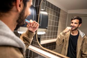 a man brushing his teeth in front of a mirror at The Bee Hostel in Amsterdam