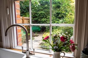a window with a vase of flowers on a window sill at Railway Cottage with garden & parking in heart city in Derby