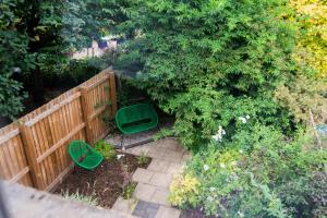 einen Blick über einen Garten mit einem Zaun und zwei grünen Stühlen in der Unterkunft Railway Cottage with garden & parking in heart city in Derby