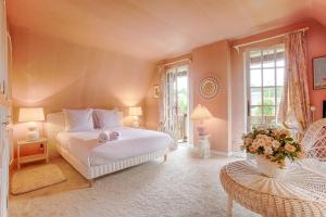 ein Schlafzimmer mit einem weißen Bett und einer Vase aus Blumen in der Unterkunft La Côte Fleurie - 5 Bdr - Garden & Jacuzzi - Tourgéville Plage in Deauville