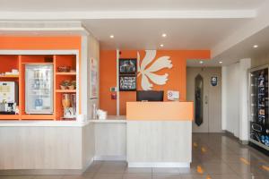 a restaurant with orange walls and a counter at Premiere Classe Lyon Beynost in Beynost