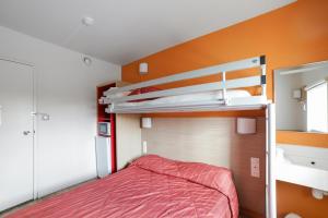1 dormitorio con 2 literas y pared de color naranja en Premiere Classe Lyon Beynost, en Beynost