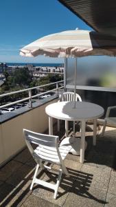 einen Tisch, Stühle und einen Regenschirm auf dem Balkon in der Unterkunft Studio calme avec terrasse vue mer in Pléneuf-Val-André