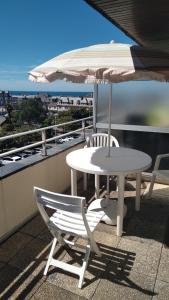 a table and chairs and an umbrella on a balcony at Studio calme avec terrasse vue mer in Pléneuf-Val-André