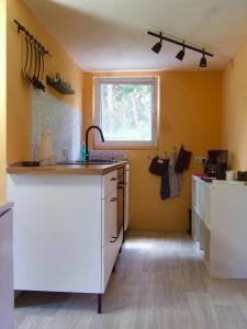 a kitchen with yellow walls and white cabinets and a window at Ferienwohnung am See in Wochowsee