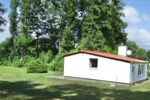 a small white building in a field with trees at Ferienwohnung am See in Wochowsee