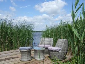 three wicker chairs and a table on a dock near the water at Ferienwohnung am See in Wochowsee