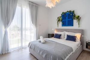 a white bedroom with a large bed with blue pillows at Lemon Tree 1-BR Apt in Livadia in Larnaka +16 photos