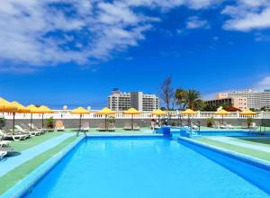een groot zwembad met parasols en stoelen bij COZY STUDIO, WIFI FREE POOL VIEW in Playa de las Americas