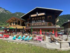 een groot gebouw met stoelen en parasols ervoor bij Le Schuss in Châtel