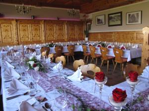 a long dining room with tables and chairs and red roses at Hotel-Gasthof Deixelberger in Wolfsberg