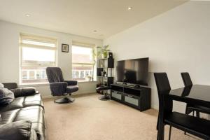 a living room with a couch and a flat screen tv at Comfy 2 Bedroom Apartment near Edinburgh City Centre in Edinburgh