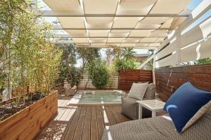 a patio with a hot tub on a wooden deck at Stelia Mare Boutique Hotel in Naousa