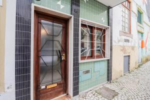 eine Holztür auf einem Gebäude neben einer Straße in der Unterkunft Casa da Fonte - Vintage House and Rooftop in Figueira da Foz