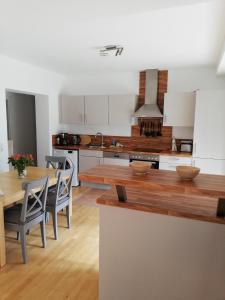 une cuisine avec une table et des chaises et une cuisine avec des placards blancs dans l'établissement Ferienwohnung Jonas, à Gödnach